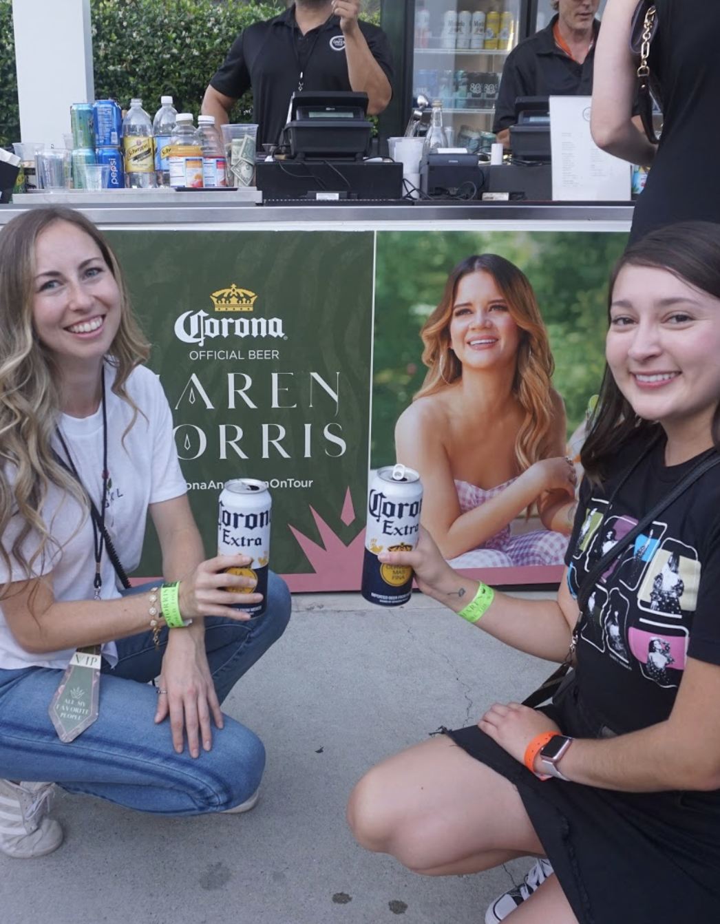Two women posing with Corona Beer in front of a Maren Morris Banner