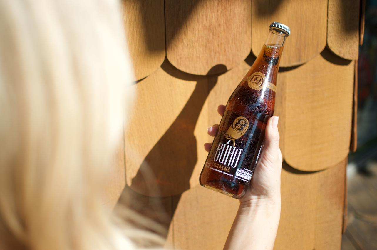 Woman Holding a Refreshing Bottle of Buho Soda