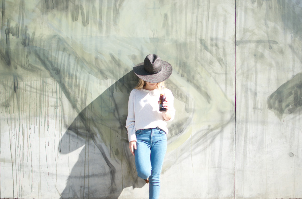 Woman standing on a wall with a bottle of Buho Soda