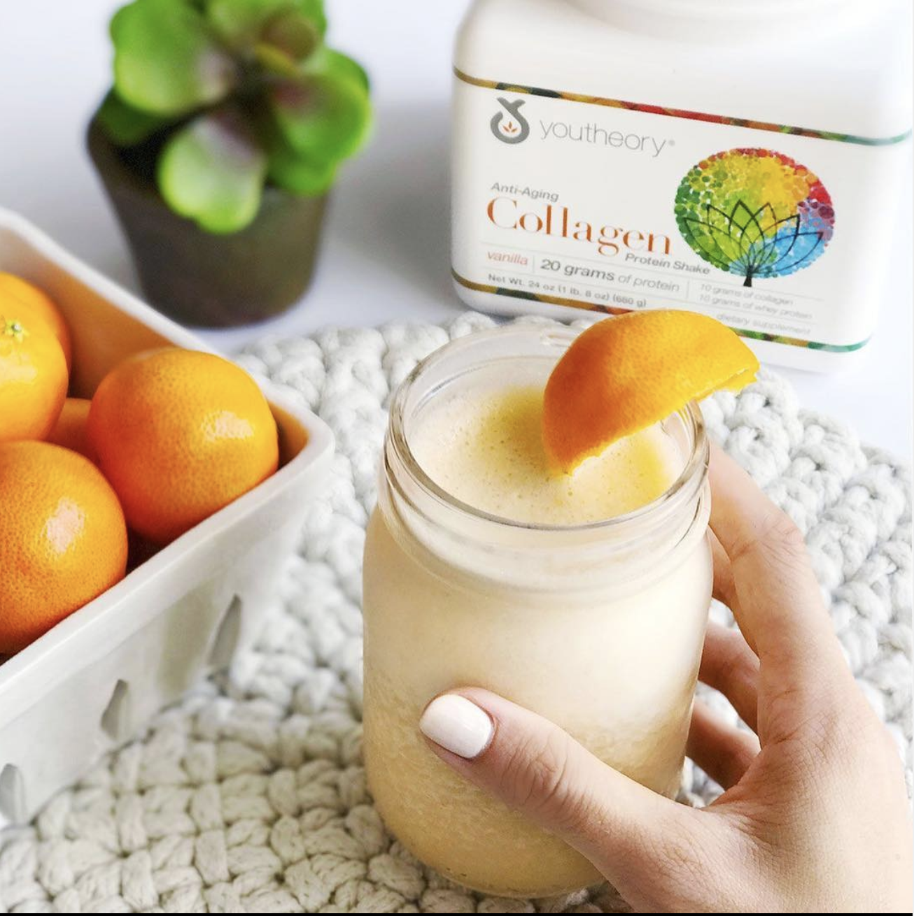 Youtheory Collagen powder with womans hand holding a beverage underneath an orange slice